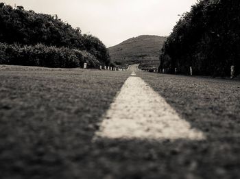 Surface level of road amidst trees against sky