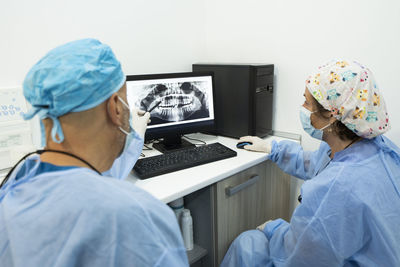 Dentists analyzing x-ray on computer screen at clinic