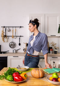 Young and beautiful housewife woman cooking in a white kitchen