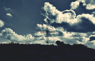 Low angle view of silhouette communications tower against sky