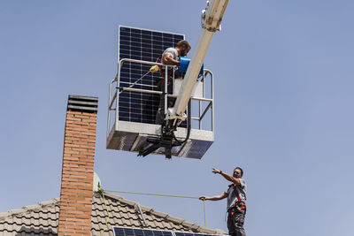 Electricians with solar panel on roof of house