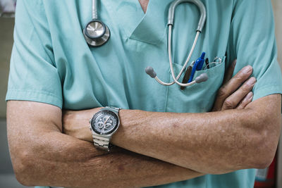 Unrecognizable man in scrubs keeping arms folded while working in hospital