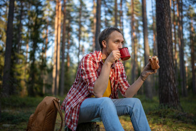 Young woman sitting on tree trunk in forest