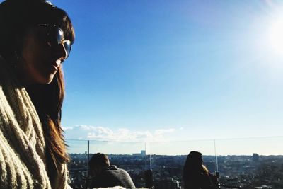Woman looking at city against clear blue sky