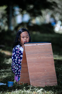 Portrait of young woman standing against trees