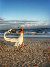 Woman at beach by sea against sky