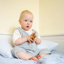 Cute baby girl sitting on bed at home