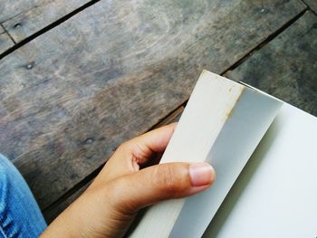 Cropped hand holding book on wooden table