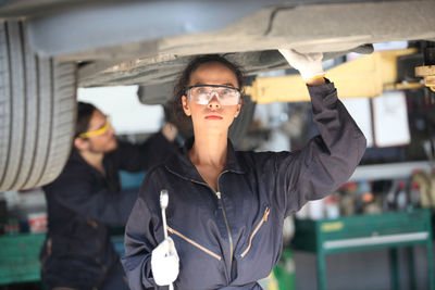 Woman working while standing under car in garage