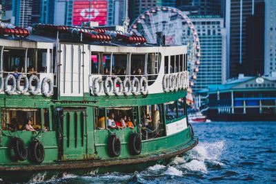 People on boat in river against city