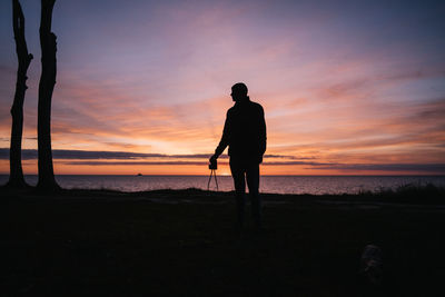 Silhouette of man standing on beach during sunset