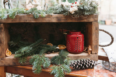 Diy natural christmas decoration and red candle lantern outdoor. pine branch with pine cone in box