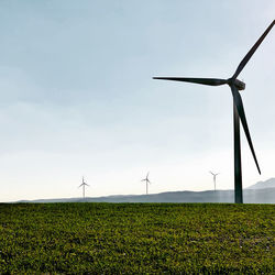 Wind turbines on field against sky