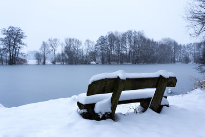 Snow covered bench on field during winter