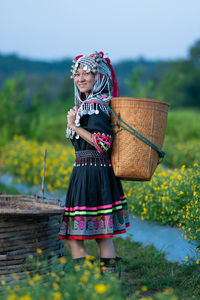 Woman wearing hat while standing in basket on field