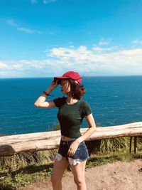 Rear view of woman standing by sea against sky