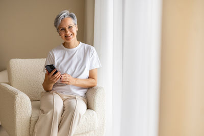 Young man using mobile phone while sitting on sofa at home