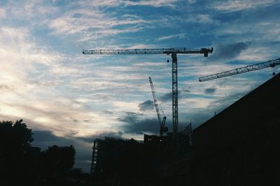 Low angle view of crane against cloudy sky