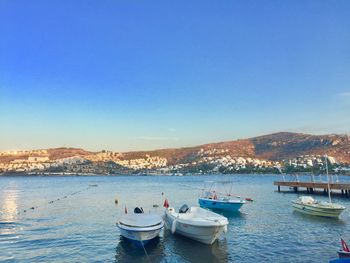 Sailboats moored on sea against clear blue sky