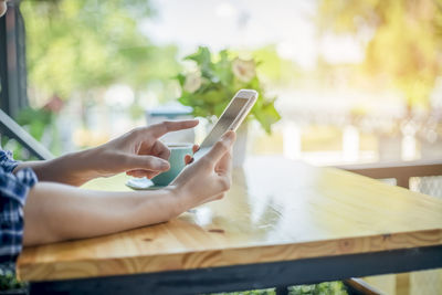 Midsection of man using mobile phone on table