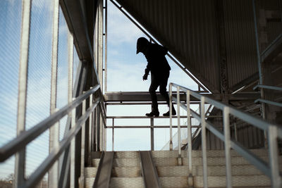 Low angle view of silhouette man walking on staircase of building