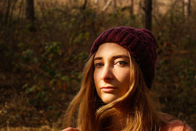Portrait of young woman wearing knit hat in forest