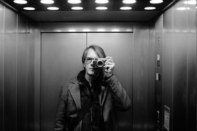 Portrait of man photographing in elevator