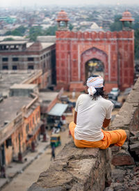 Rear view of man sitting on retaining wall