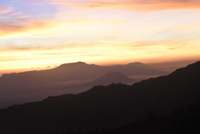 Scenic view of silhouette mountains against orange sky
