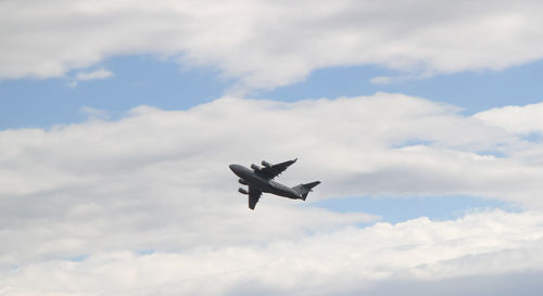 Low angle view of airplane flying against cloudy sky