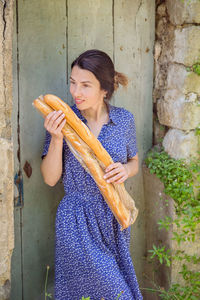 Young woman standing with french baguettes in the countryside