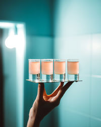 Bartender's hand holding cocktails shots in restaurant, pub or night club in neon colours