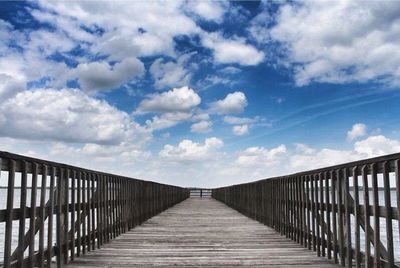 Pier on sea against cloudy sky