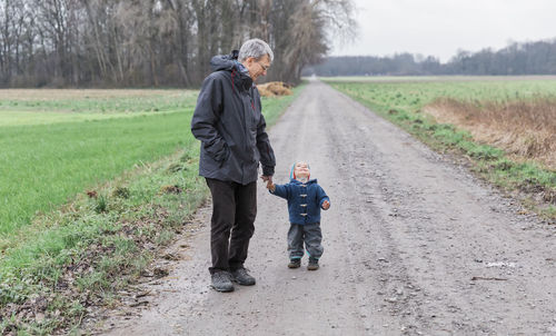 Full length of father and daughter on road amidst field