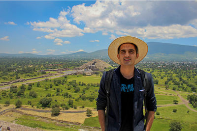 Portrait of smiling man standing on landscape against sky