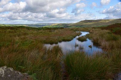 Scenic view of moorland with lake on cloudy day