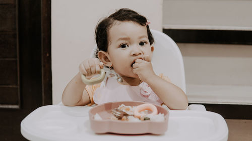 Portrait of cute girl eating food at home