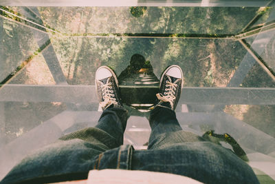 Low section of man standing on glass