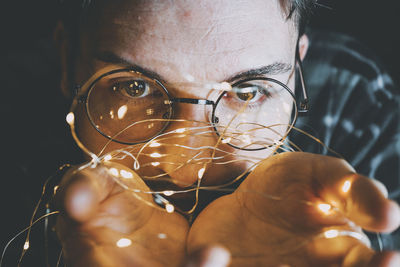 Close-up of man holding string light