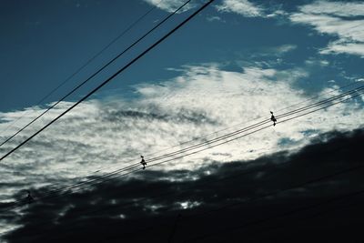 Low angle view of silhouette electricity pylon against sky