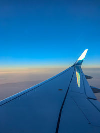 Close-up of airplane wing against clear blue sky