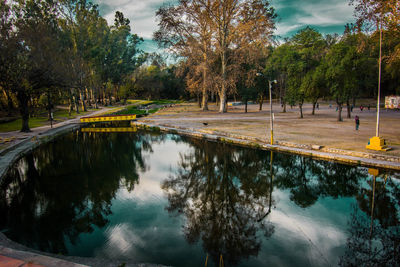 Scenic view of park by lake against sky