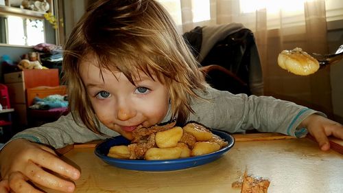 Portrait of girl eating food at home