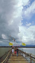Pier on sea against cloudy sky