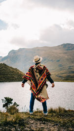 Rear view of man standing by lake