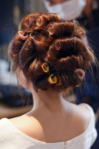 Rear view of woman with hair curlers at salon