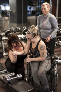 Woman on wheelchair training in gym with personal trainer