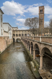 Arch bridge over river against sky