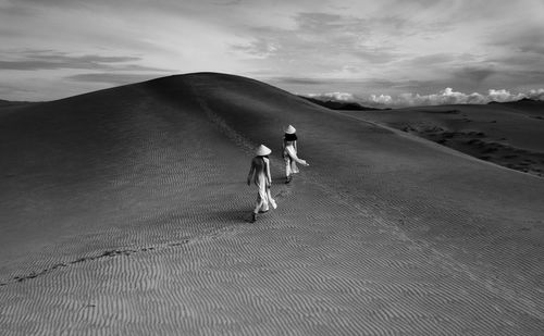 Rear view of woman walking on sand