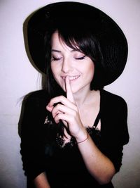 Young woman with finger on lips against wall